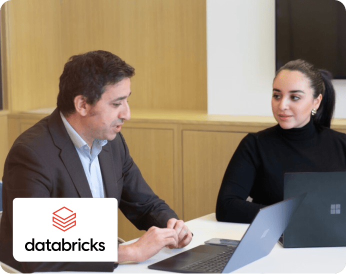 un homme et une jeune femme discutant en réunion avec le logo databricks partenaire